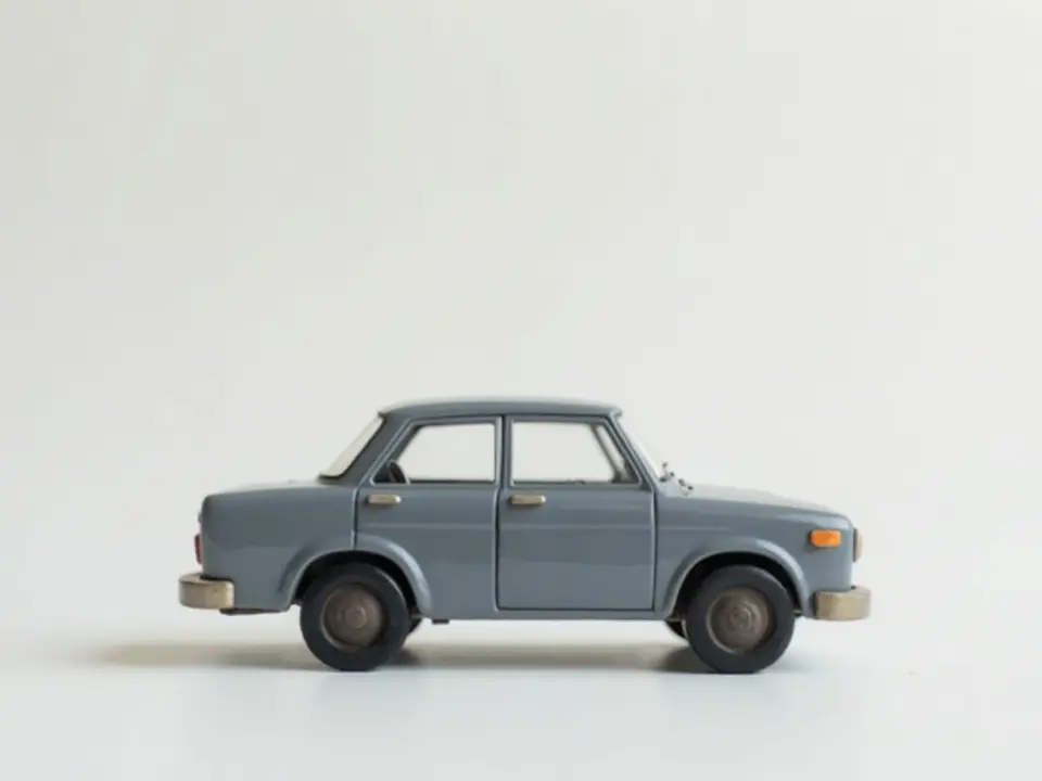 A grey toy model car photographed side-on against a cool white background, filling a tighter frame
